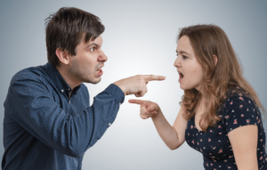Man en vrouw wijzen naar elkaar en geven elkaar de schuld