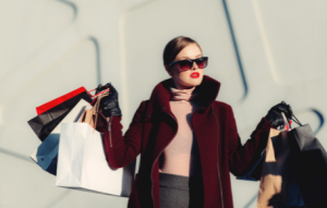 Vrouw in luxe kleding met meerdere tassen in haar handen. Het tegenovergestelde van begeerteloosheid